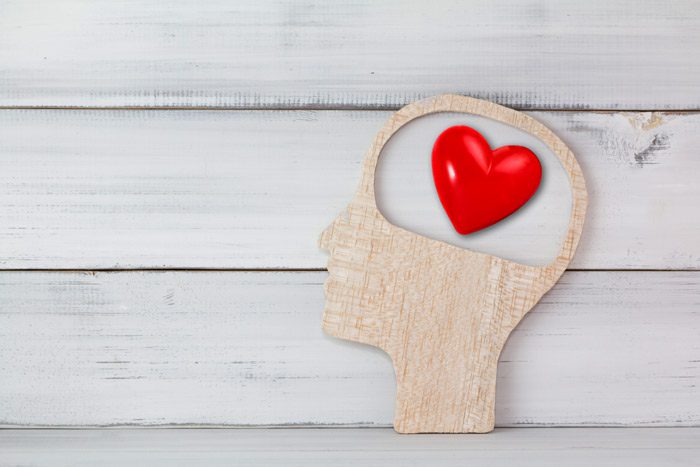 wooden cutout of human head with heart in the brain area - brainspotting