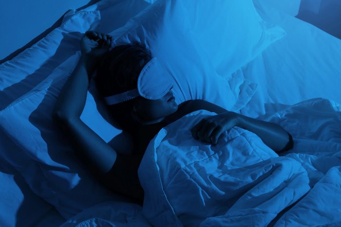 all cool blue tones/shadows - woman asleep in bed with eye mask - good sleep hygiene